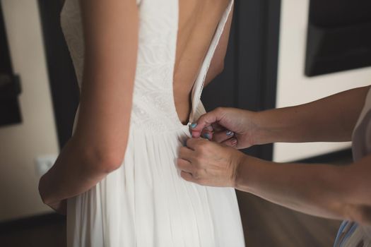 A friend helps to dress the bride's wedding dress.