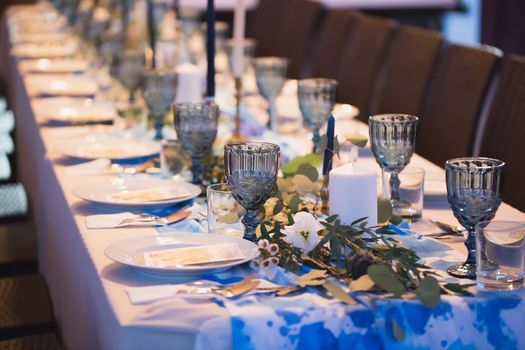 Wedding banquet. Table setting with blue glasses.
