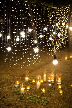Wedding ceremony evening with candles and lamps in the coniferous pine forest.