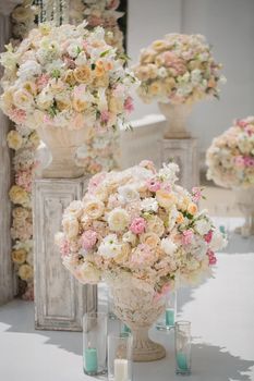 Beautiful bouquet of roses in a vase on a background of a wedding arch. Beautiful set up for the wedding ceremony