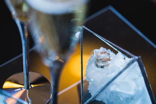 Beautiful elegant wedding rings in a glass box on a white flower