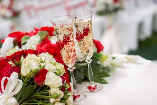 The champagne glasses. Wedding ceremony outdoors. Bouquet with red flowers