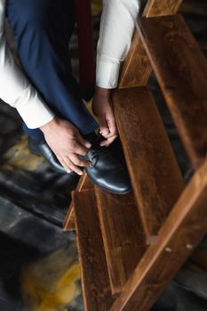 Man tying shoes laces on the wooden floor.