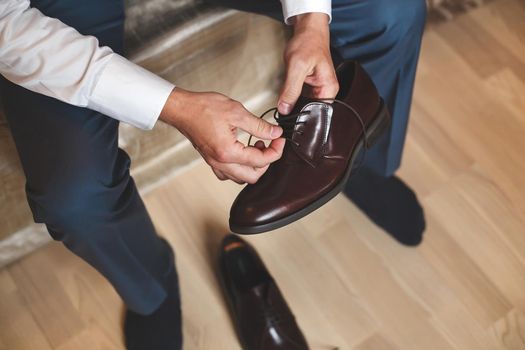 Groom putting his wedding shoes. Hands of wedding groom getting ready.