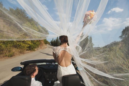 Beautiful stylish young successful couple enjoying riding in the car at wedding walk in the tropical country or island.