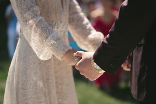 Bride and groom hold hands during the wedding ceremony.