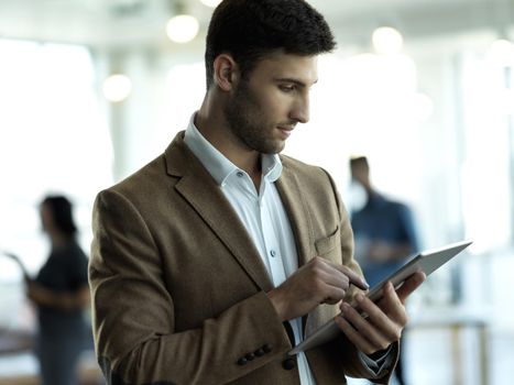 Success is the only thing on his mind. Cropped shot of a handsome young businessman working on a tablet in his office.