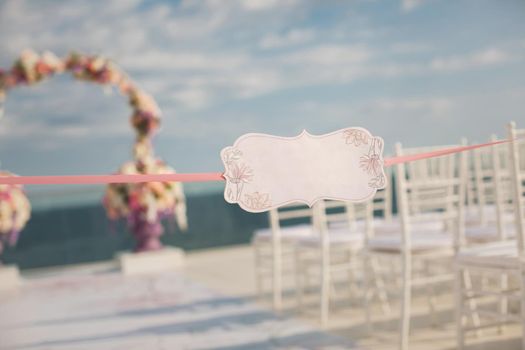A sign on the backdrop of wedding arch and the sea