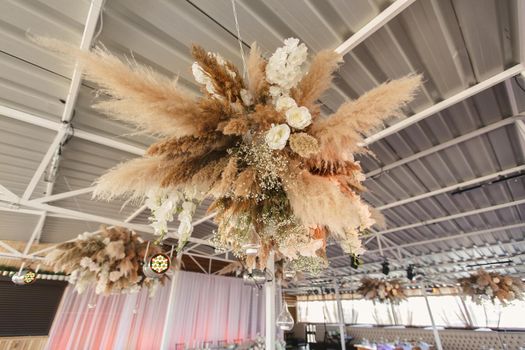 Wedding decor for newlyweds at a banquet. Floristry of dried flowers and candles in boho style