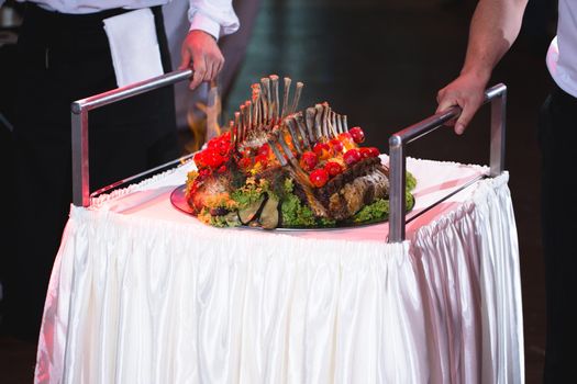 A waiter takes out a square of lamb at a wedding banquet