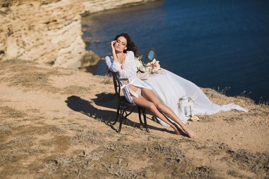 Girl in lingerie on top of a mountain overlooking the ocean. Charges of the bride, bride's morning