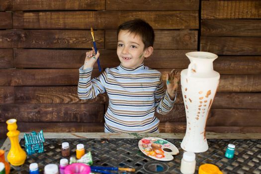 a child paints a vase in the garage.