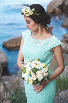 Bride in nature in the mountains near the water. Dress color Tiffany. Bride posing with bouquet