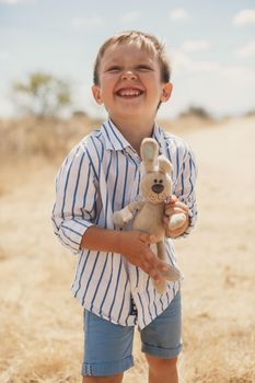 Happy boy holding a toy rabbit. Hare