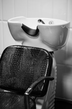 The black leather recliner next to the sink in the Barber shop. Black and white.