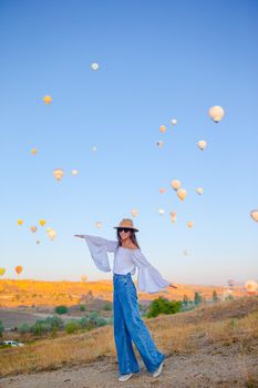 Happy woman during sunrise watching hot air balloons in Cappadocia, Turkey