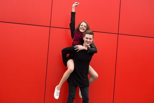Happy people jump on the background of a red wall.