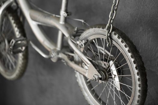 Silver bike hanging on chains against the wall in the Studio