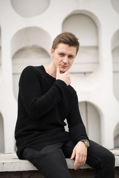 Fashion young man in black clothes on white wall background