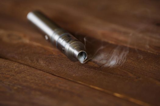 Electronic cigarette on a wooden table. Smoke