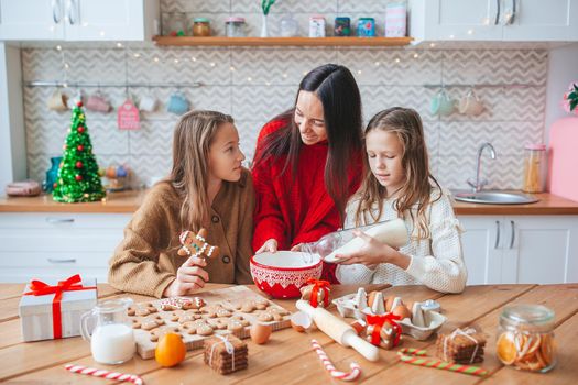Happy family mother and daughters bake cookies for Christmas