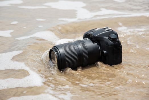 DSLR camera with telephoto lens on a beach it wet from water sea wave when travel and test using in the extreme environment demo waterproof by photographer