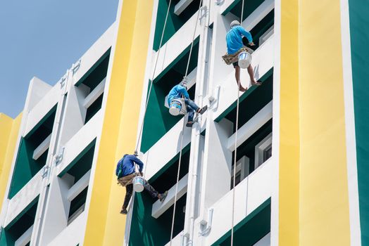 Bangkok, Thailand - April 23, 2017 : Unidentified asian construction painter was climbing the building by rope with safety to painted at wall for  maintenance renovating or repair