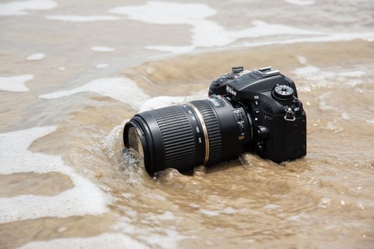Rayong, Thailand - May 27, 2017 : Unidentified photographer demo waterproof DSLR camera with telephoto lens on beach it wet from water sea wave when travel and test using in the extreme environment