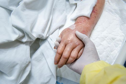 Patient in the hospital with saline intravenous and relatives patient hand holding a elderly patient hand
