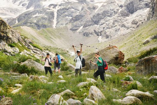 Women with backpacks and scandinavian sticks climb the mountains