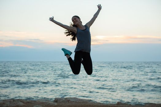 Sport girl jumping on beach at sunset