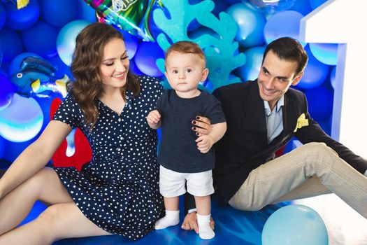 Father, mother and son on the background of blue decor in the marine style at the holiday
