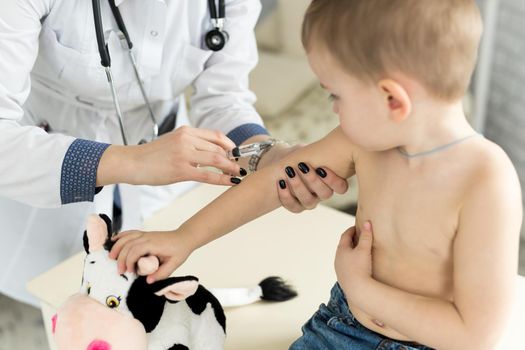 Doctor pediatrician giving child an intramuscular injection in arm.