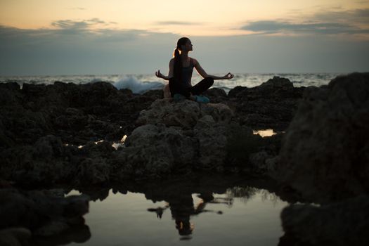Caucasian woman practicing yoga at seashore of ocean.