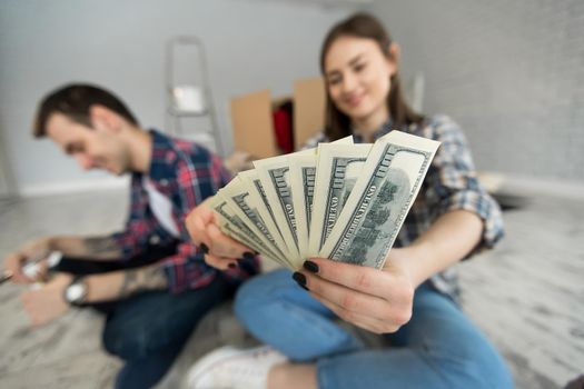 Young couple counting money while sitting on floor in new apartment.
