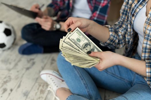 Young couple counting money while sitting on floor in new apartment.