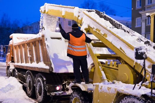 Claw loader vehicle removes snow from the road. Snow plow machine and snow truck clean the streets of snow in city.
