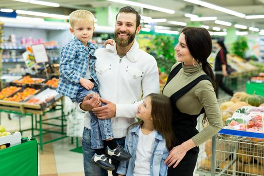 Portrait of a young family with a son and daughter in a supermarket.