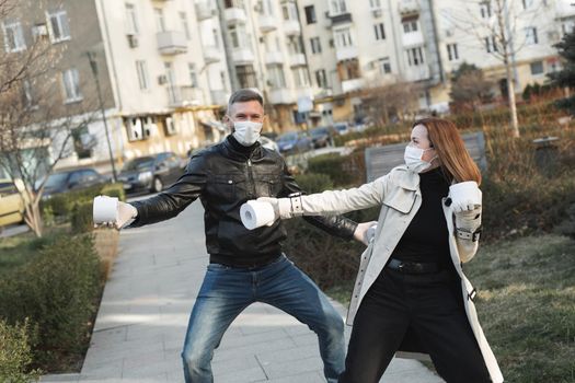 Woman and a man in a coronavirus face mask hold large rolls of toilet paper on a city street and indulge.