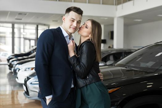 A couple of men and women are happy to buy a new car in a car dealership.