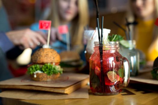 Burger and cocktail on a wooden table in a restaurant close-up