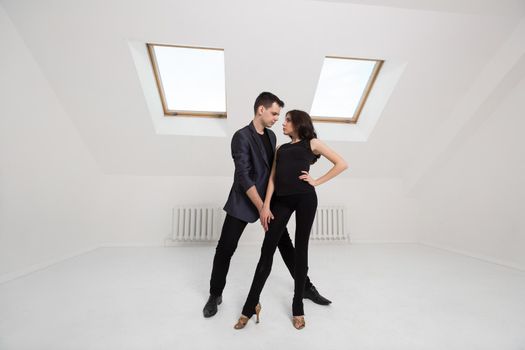 beautiful couple dancing bachata on white background in studio.