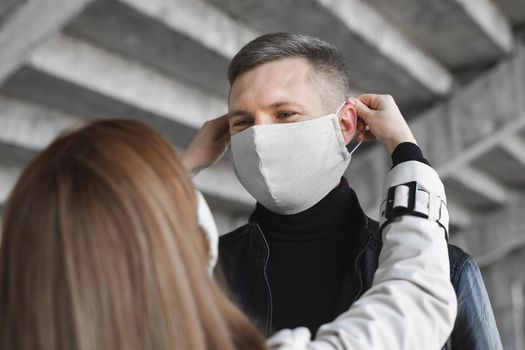 Woman puts a protective mask on a man's face. Coronavirus, covid19