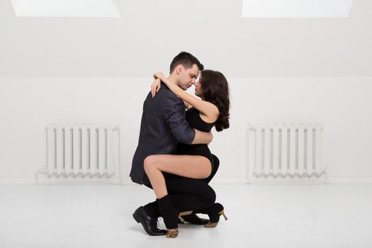 beautiful couple dancing bachata on white background in studio.