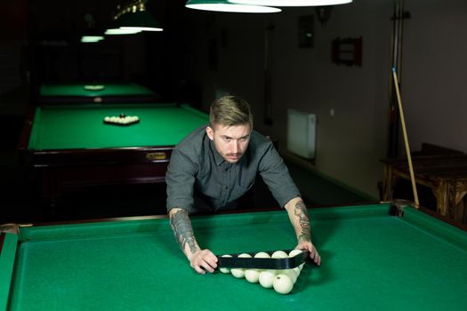 Triangle of billiard balls. A man getting ready to start a game of billiards.