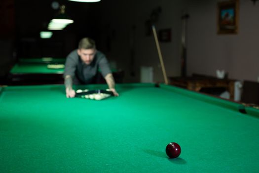 Game of billiards. The man puts the balls on the green billiard table