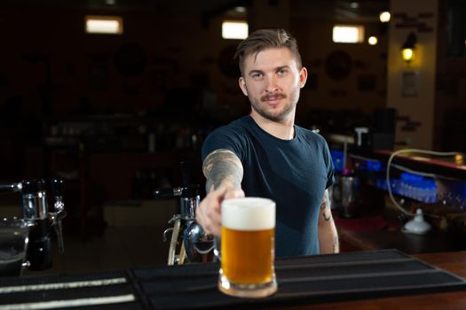 Close up of handsome barman holding a pint of beer in a pub.