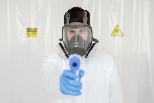 Doctor wearing protective mask ready to use infrared forehead thermometer to check body temperature for virus symptoms - epidemic virus outbreak concept. Coronavirus.Thermometer gun