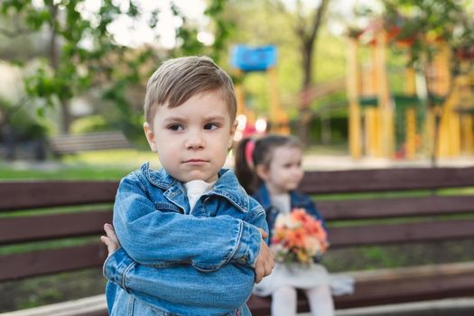 Date of a little boy and a girl in the park with a bouquet of flowers. The boy was offended
