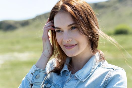 Close-up portrait of a young beautiful woman in nature on a hill background